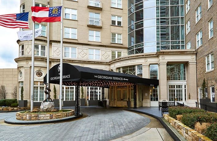 Hotel entrance with black awning labeled "The Georgian Terrace." Flags are displayed on poles, and the building features large windows and brick architecture.