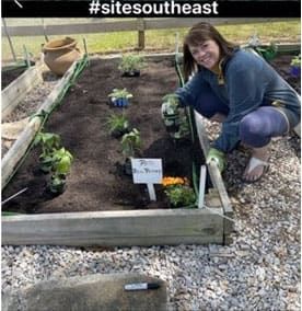 woman planting flowers, working in her raised bed garden.